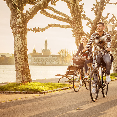 Zwei Studierende fahren auf Fahrrädern am Seerhein entlang