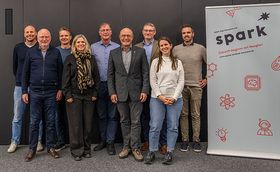 Eine Gruppe von 9 Personen strahlen in die Kamera 