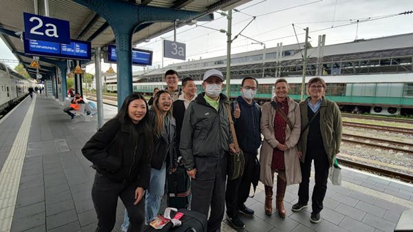 Eine Gruppe lachender Menschen aus Deutschland und Taiwan stehen an einem Bahnsteig. 