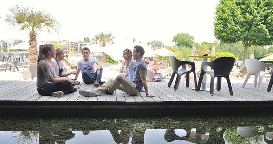 Studierende sitzen auf Holzsteg in Strandbar und reden