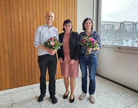 Gruppenfoto der gewählten INM-Leitungen Prof. Hettich und Prof. Lau und der HTWG Präsidentin Prof. Rein. Prof. Hettich und Prof. Lau halten Blumensträuße in der Hand