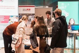 Vier Studierende informieren sich an einem Infostand.