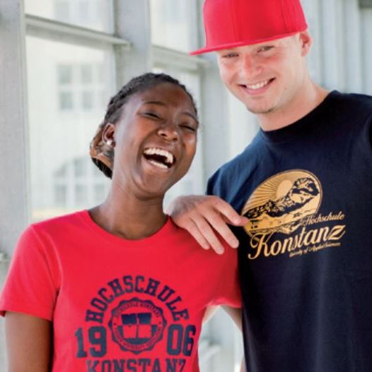 [Translate to English:] Eine junge  Frau und ein junger Mann lachend in HTWG-T-Shirts