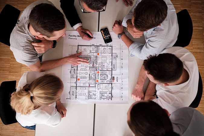 Studierende und Prof über einem Plan