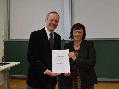 Prof. Pischel und Prof. Rein präsentieren die Urkunde zur Verleihung der Honorarprofessur