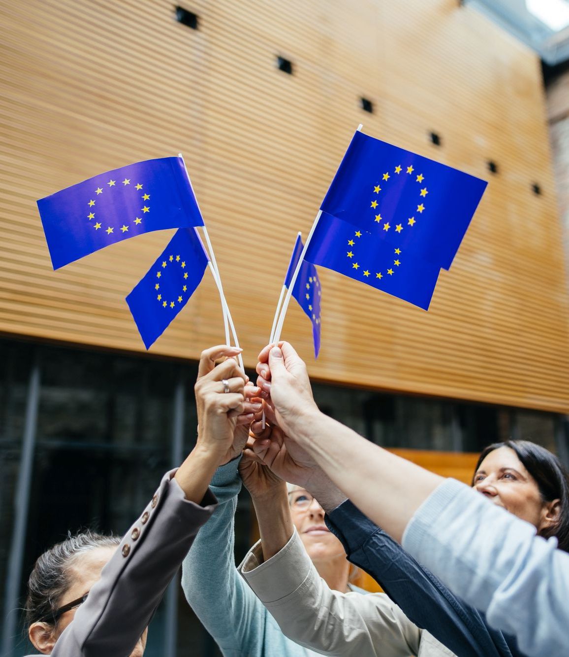 Eine Gruppe Erwachsener halten vereint Europaflaggen in die Luft