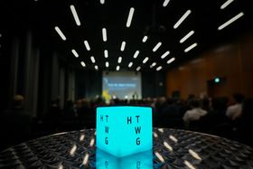 Ein grüner Leuchtwürfel in einem schwarzen Saal