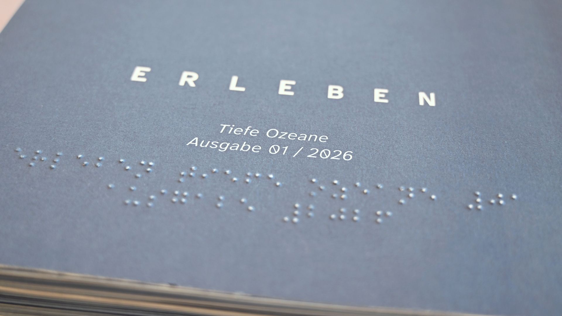 Titel des Magazins "Erleben" in normaler Schriftund Braille-Schrift