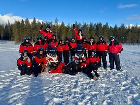 Gruppenfoto von Menschen in rot-schwarzen Schneeanzügen