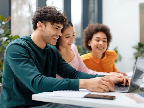 Drei Studierende bei gemeinsamer Arbeit vor einem Laptop. Bildnachweis: iStock.