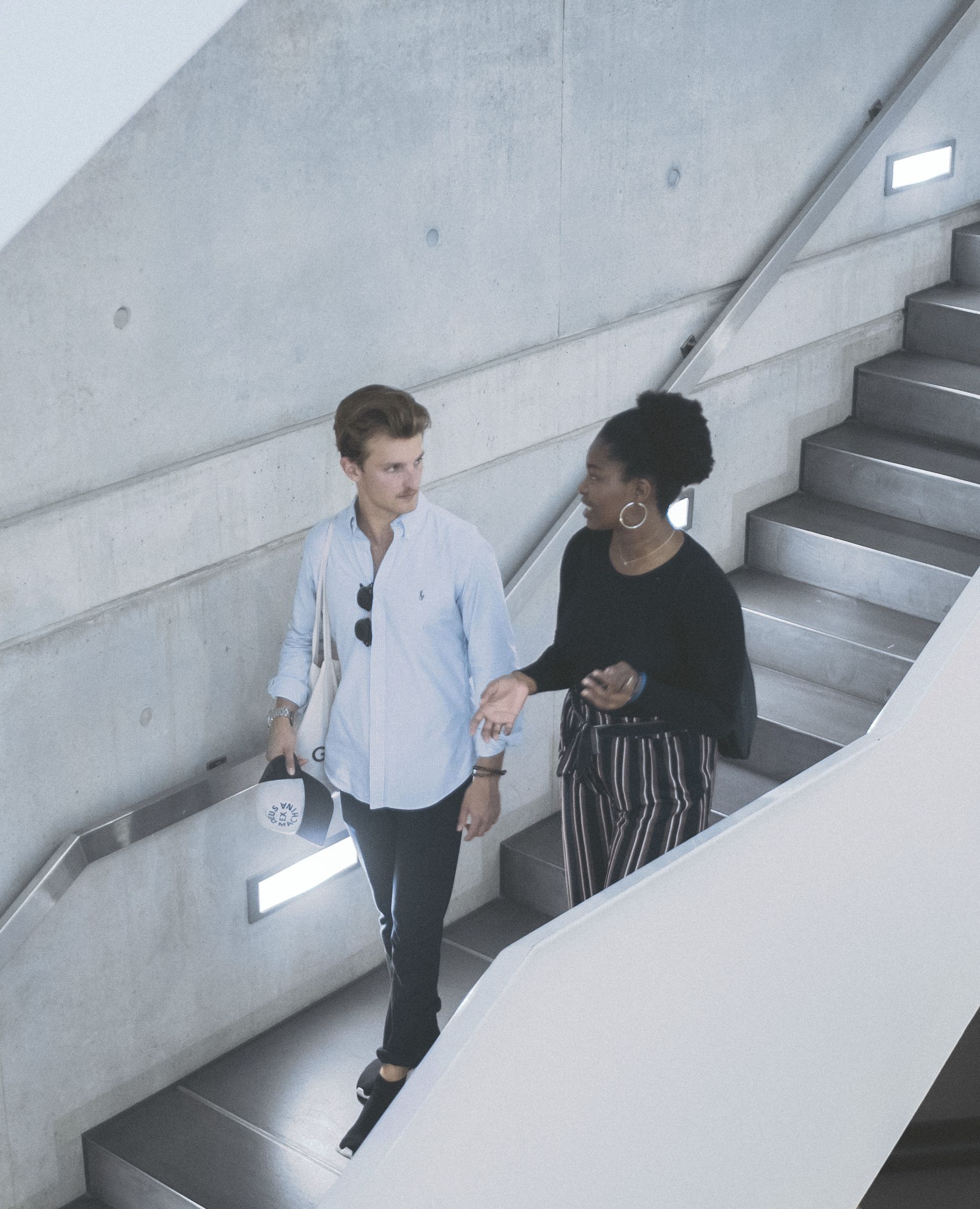 Zwei Studierende unterhalten sich auf einer Treppe in der Hochschule