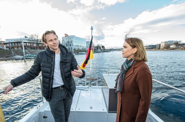 Prof. Dr. Gunnar Schubert (links) erläutert Wissenschaftsministerin Petra Olschowski (rechts) das Forschungsboot Solgenia. Sie stehen beide auf dem Deck des Bootes und fahren auf dem Konstanzer Seerhein.