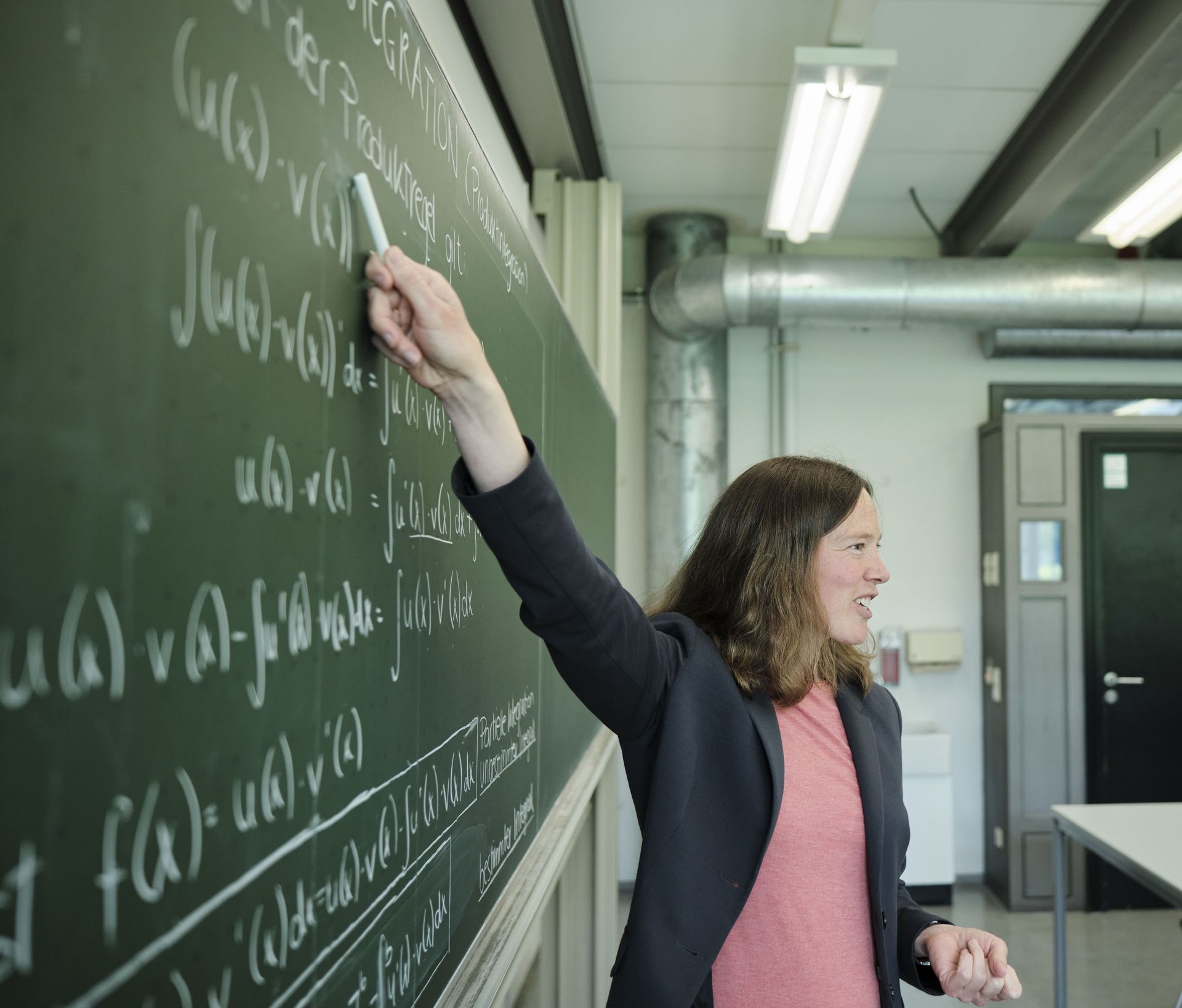 Eine Professorin steht vor einer Tafel mit mathematischen Formeln
