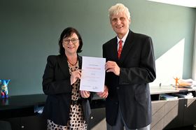 Präsidentin Rein und Professor Zerres halten gemeinsam die Dankurkunde für 25 Dienstjahre