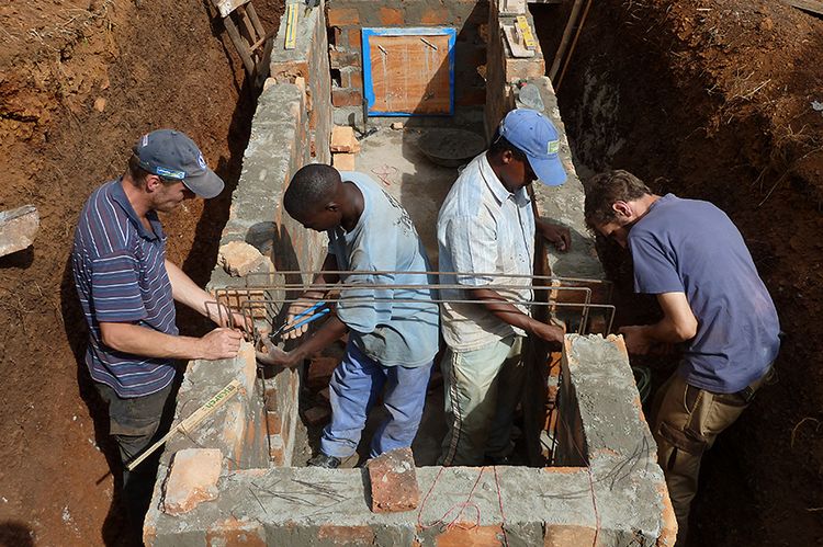 Vier Ingenieure arbeiten am Fundament eines Brückenpfeilers.