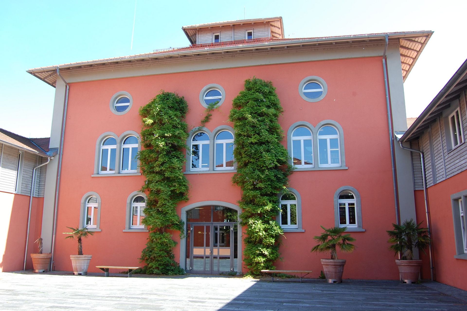 Die rote Fassade der Bibliothek im Innenhof, mit Eingang 