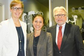 Kathrin Härle, Vera Eichberger und Vorsitzender Prof. Dr. Anton Brunner posieren fürs Foto vor einer Glaswand.