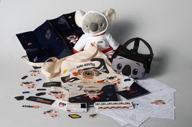 Das Bild zeigt eine Koala-Stofftier, eine VR-Brille mit Koala-Gesicht, diverse Sticker und Stofftaschen, mit dem Koalabören Jur drauf