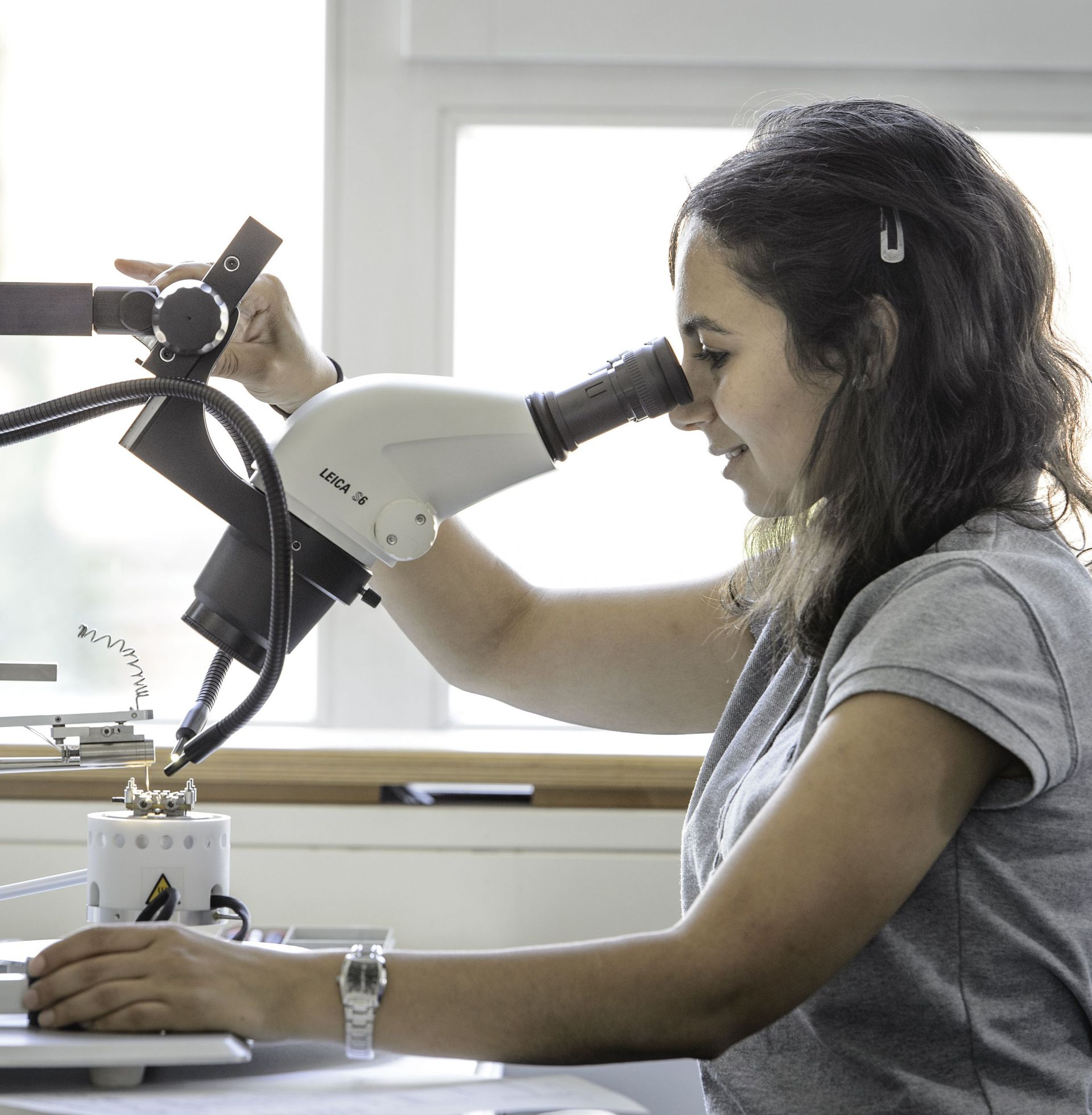 A young woman works on a device in the electronics lab