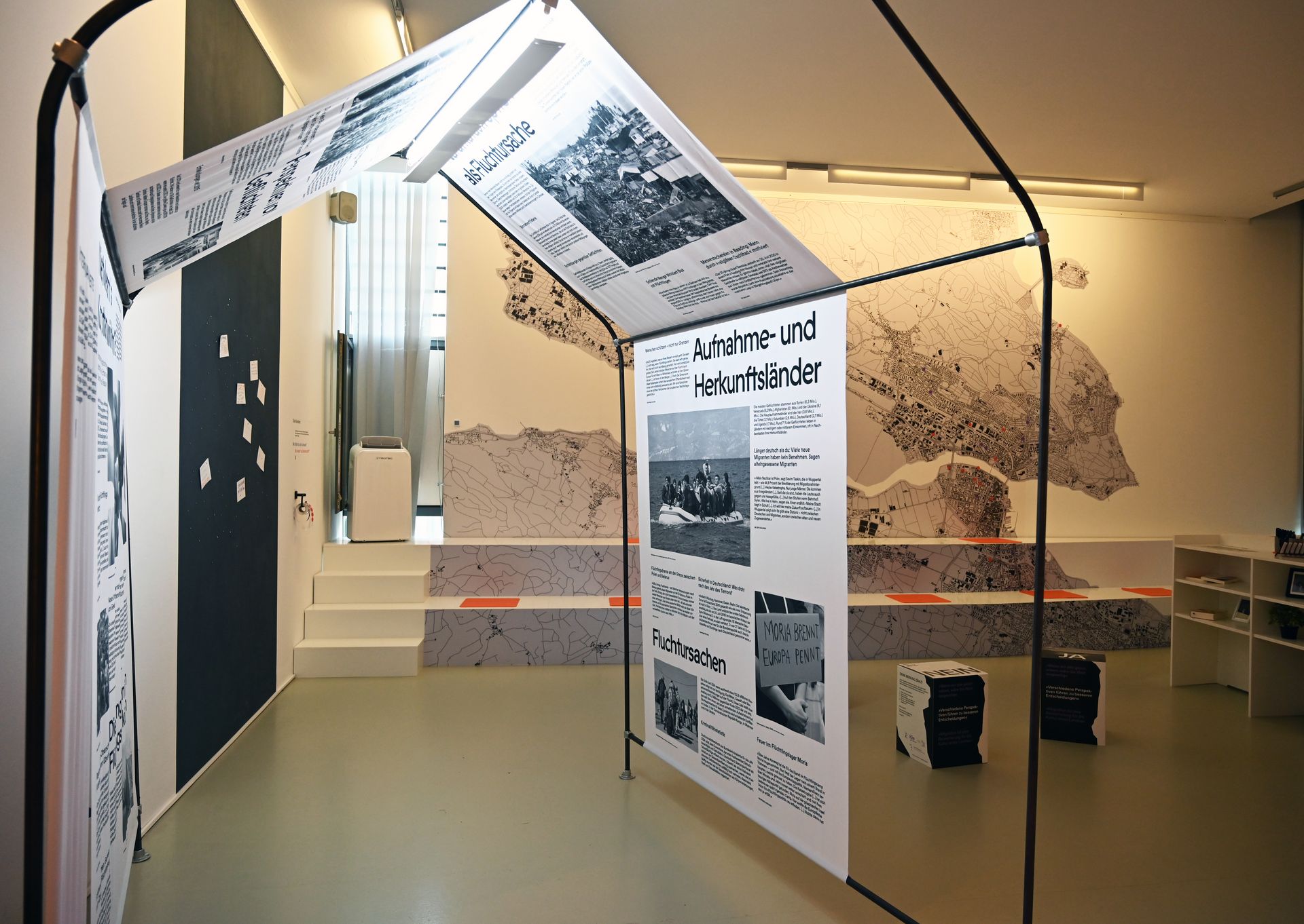 Blick in einen Ausstellungsraum mit einer Hütte aus Zeitungsberichten