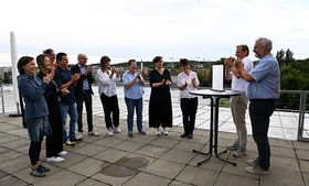 Eine Gruppe Erwachsener freut sich über die symbolische Übergabe des Leitbild Lehre 
