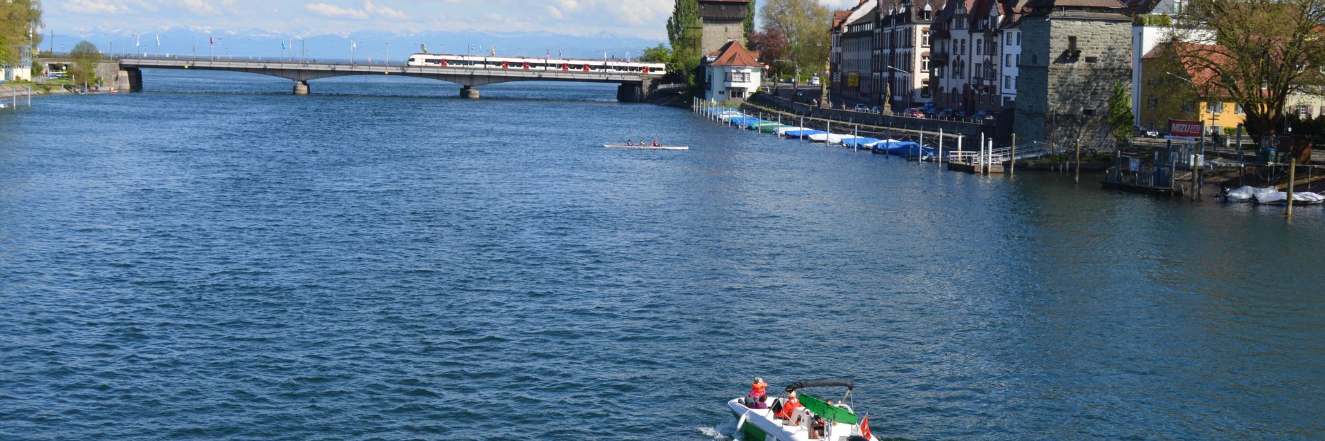 Blick über den Seerhein mit einem fahrenden Schiff im Vordergrund in Richtung alte Rheinbrücke und Bodensee