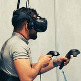 Ein Mann hat eine VR-Brille aufgesetzt und passende Controller in der Hand