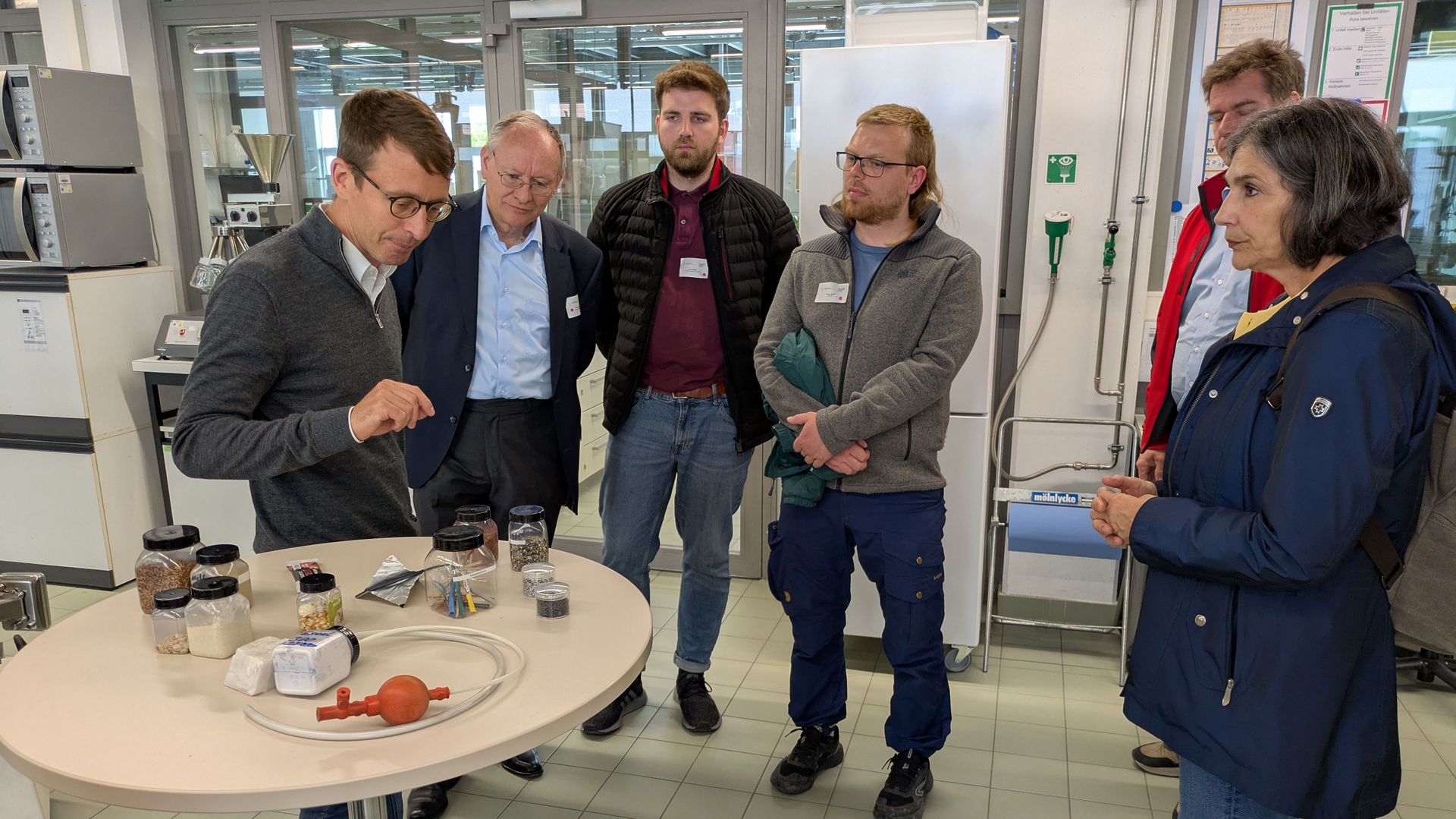 Teilnehmende hören einem Vortrag bei einer Laborführung zu und bekommen Geräte gezeigt.
