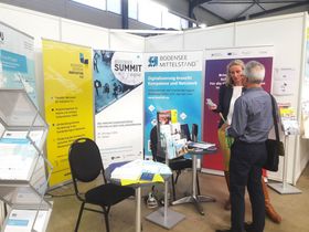 Messeszene: Ein Mann unterhält sich am Messestand des Bodenseezentrum Industrie 4.0 mit der Geschäftsführerin Alexandra Boger.