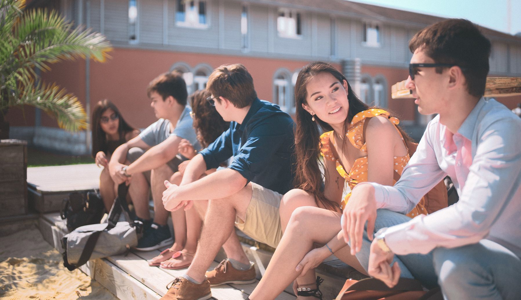 Eine Gruppe Studierender sitzen in der Sonne an der Strandbar