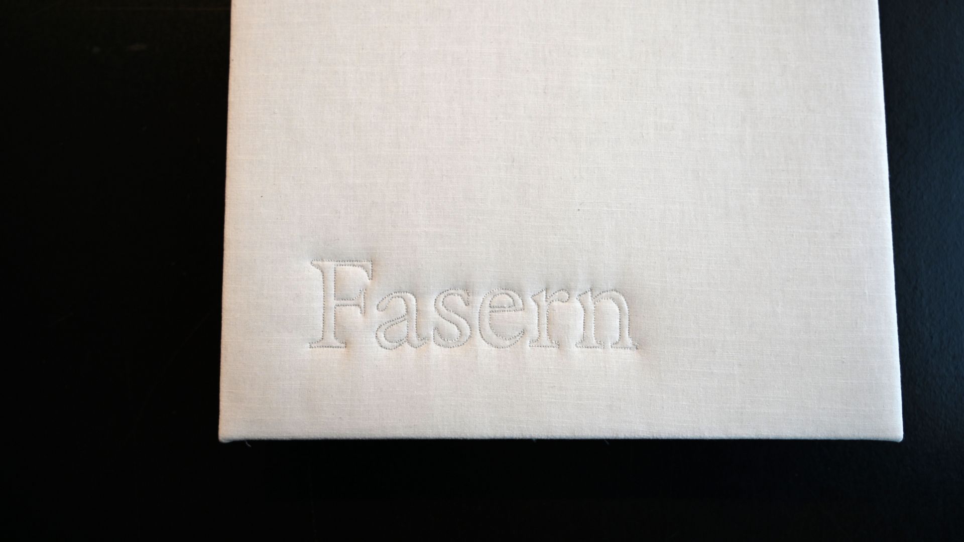 Buchdeckel aus Stoff, das Wort "Fasern" ist eingestickt