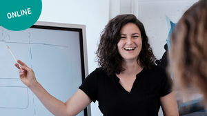 Eine Frau gestikuliert und präsentiert an einem Whiteboard