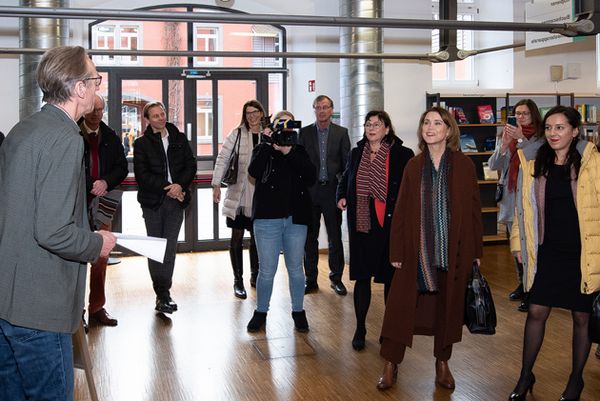 Bibliotheks-Leiter Bernd Hannemann steht rechts am Bildrand und stellte der Gruppe, die in den Raum blickt, die Bibliothek vor.