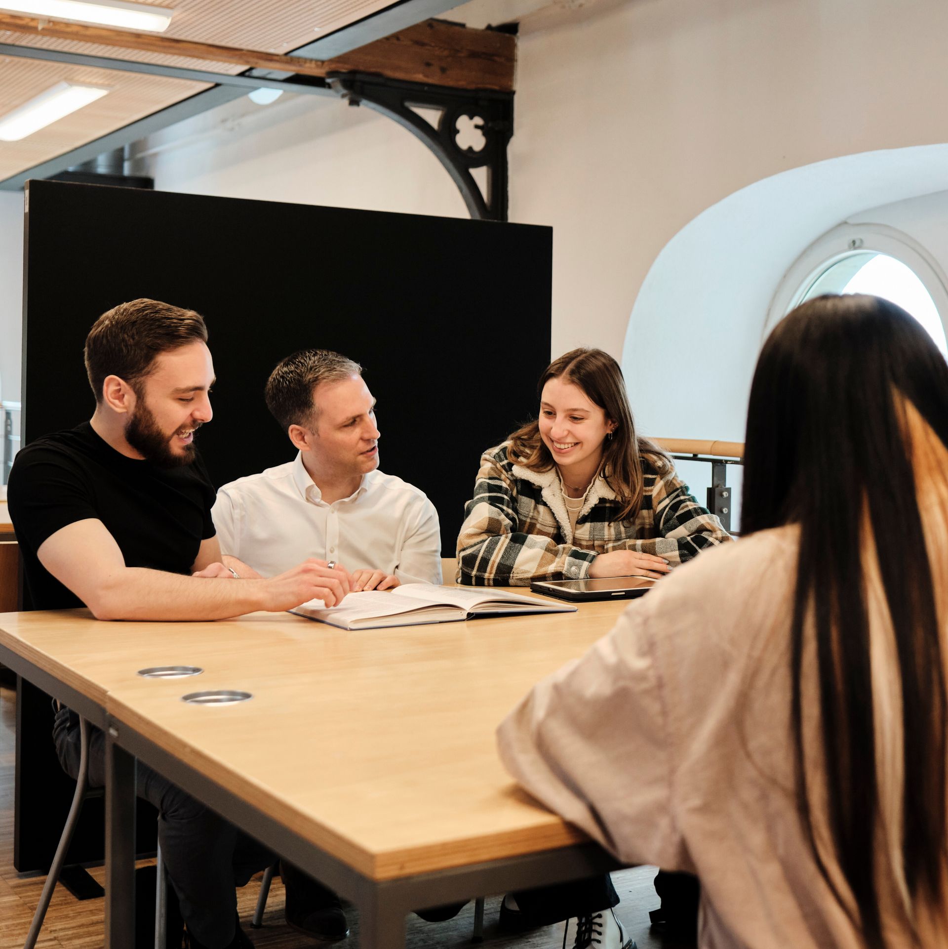 Professor bespricht sich mit Studierenden in der Bibliothek