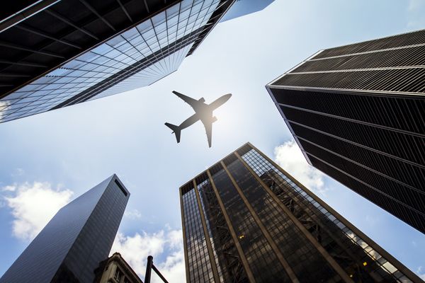 Flugzeug fliegt über Hochhäuser