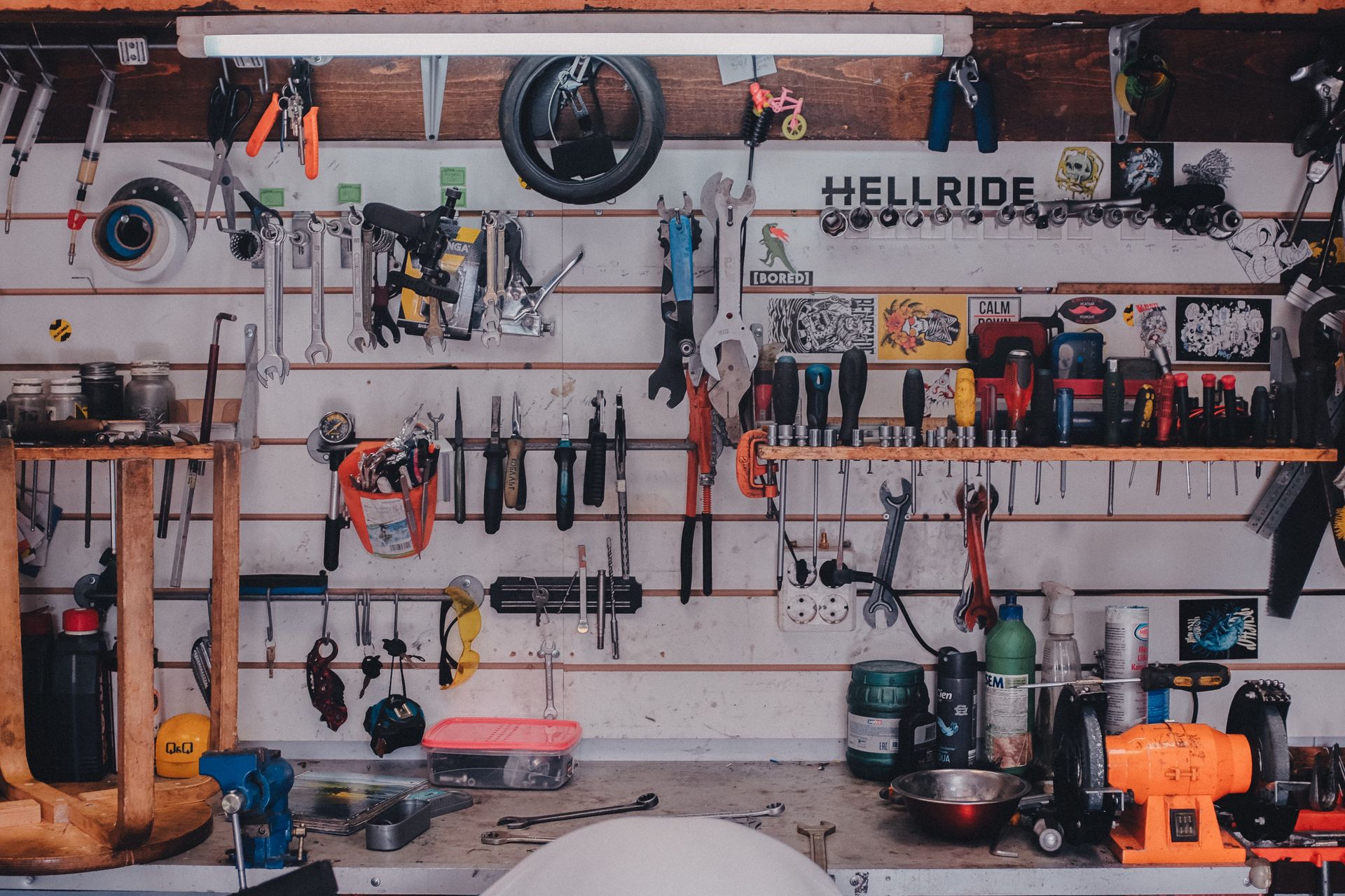 Eine Wand aus wießen Brettern hängt voll mit Werkzeug.