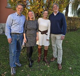 Zwei Männer und zwei Frauen stehen im Freien und lächeln in die Kamera