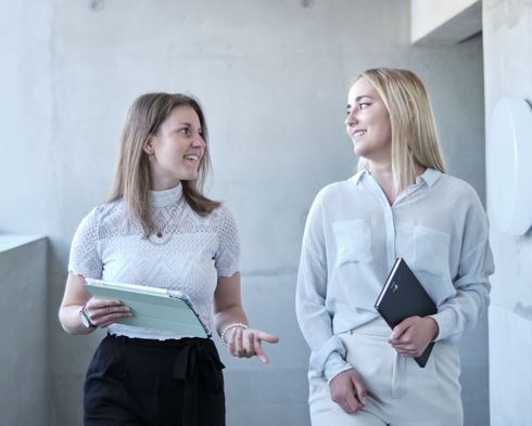 Zwei Studentinnen, die sich im Treppenhaus austauschen.