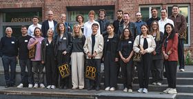 Das Bild zeigt ein Gruppenfoto der Preisträger*innen auf einer Steintreppe