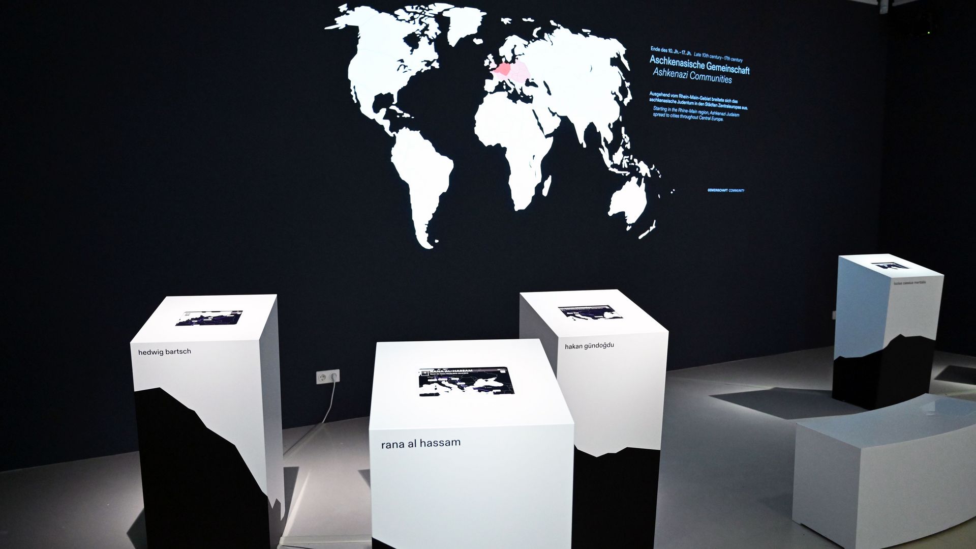 Foto aus der Ausstellung mit digitalen Pulten und einer Landkarte an der Wand