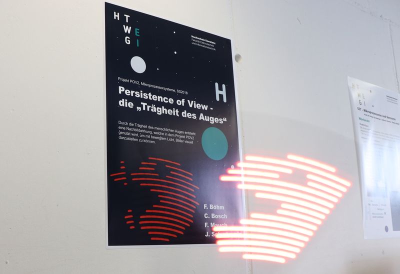 Auf dem Foto ist ein Plakat eines Exponates zu sehen und im Vordergrund das Laserbild, welches das Exponat erzuegt.