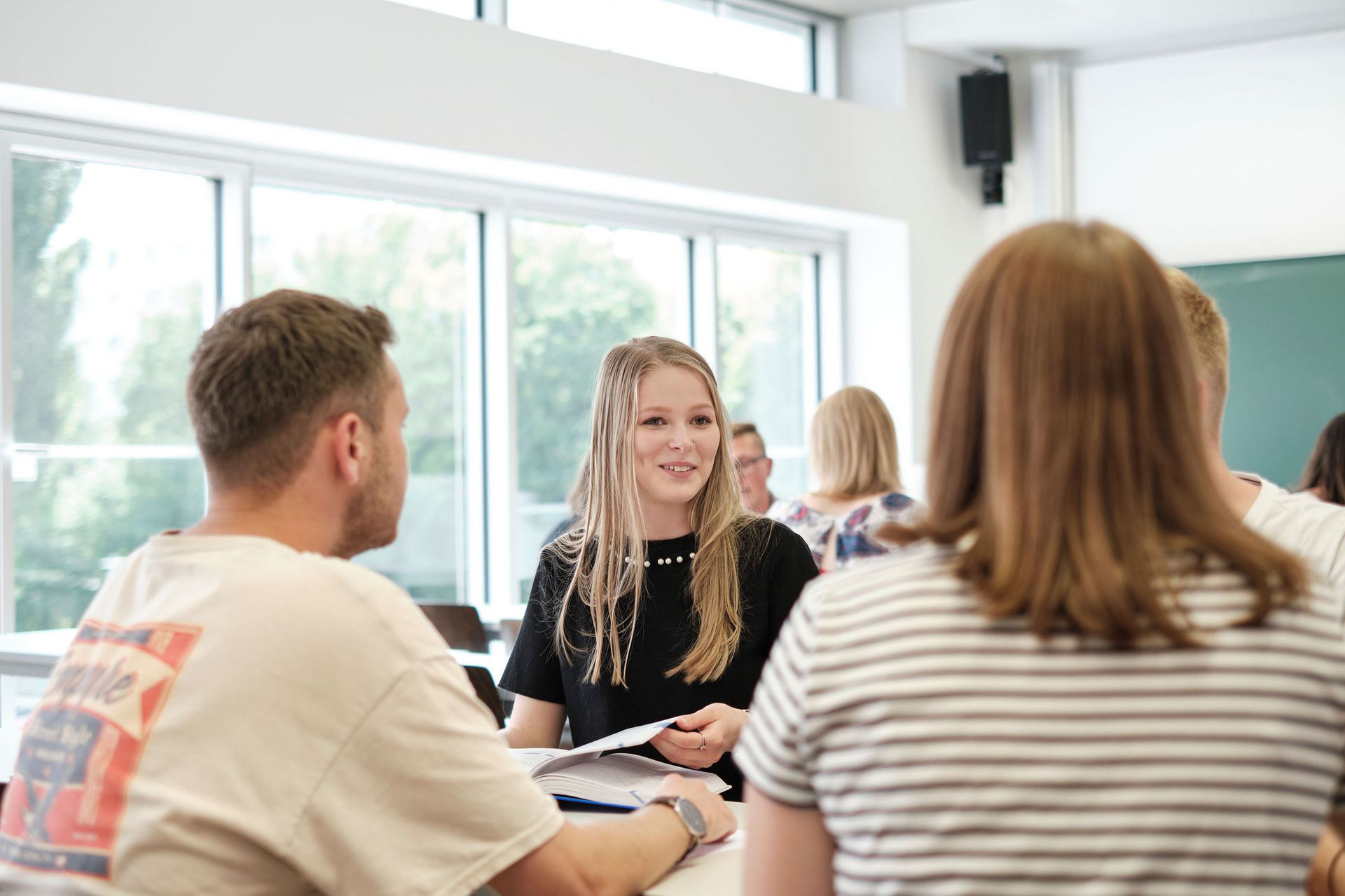 3 Studierende sitzen in einer Arbeitsgruppe zusammen