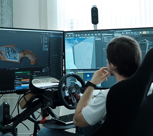 Studierender im Fahrsimulator vor Monitoren mit Software