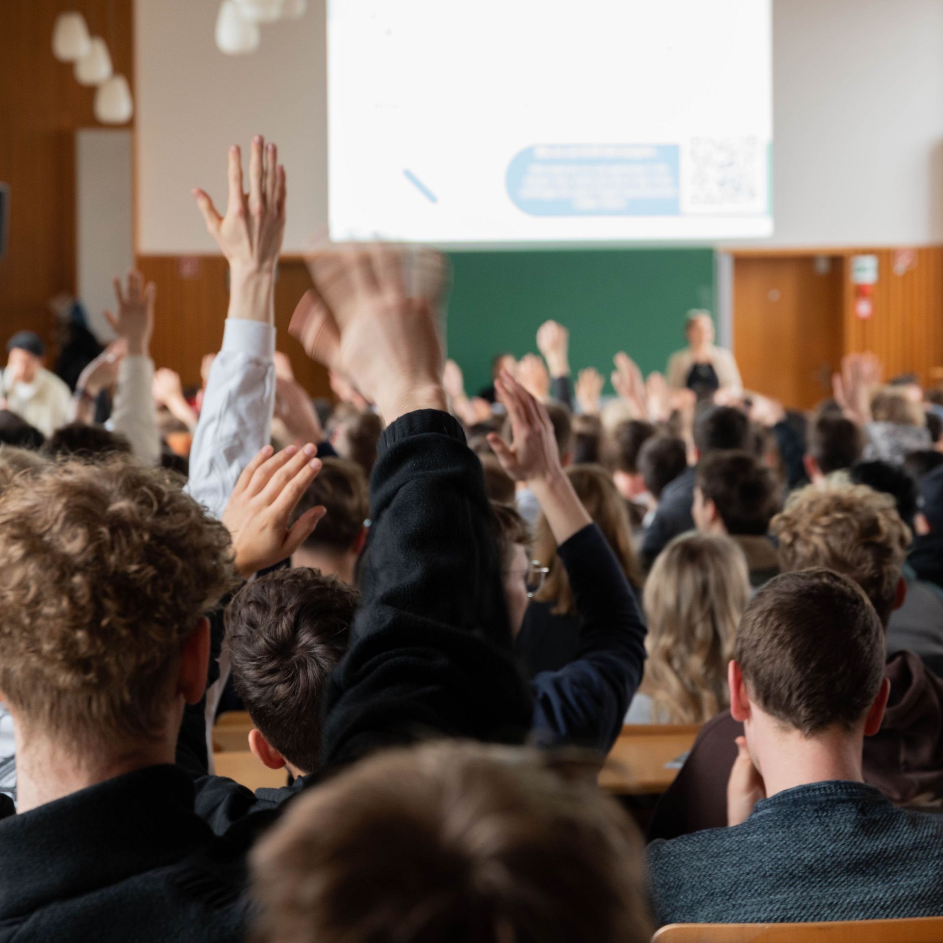 Studierende heben die Hand bei der Erstsemestereinführung in der Aula