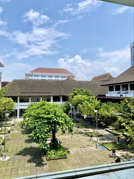 Blick aus ca. dem 1. Stock auf einen Hof mit grünen Bäumen auf dem Campus der Gadjah Mada University.