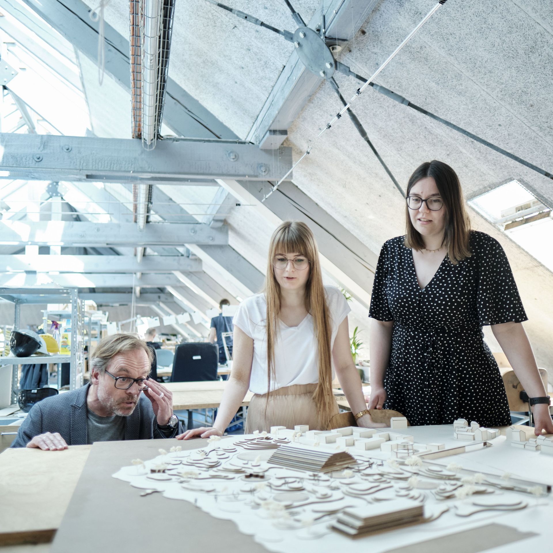 Drei Studierende diskutieren mit einem Professor über ein Architektur-Modell