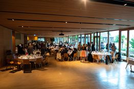 Festsaal mit eingedeckten Tischen und Feiernden
