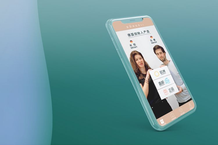 Zu sehen ist vor grünem Hintergrund der hochformatige Bildschirm eines Smartphones. Auf dem Bildschirm sind Miriam Theobald und Marcel Münch zu sehen, die zusammen ein Plakat mit chinesischen Schriftzeichen halten.