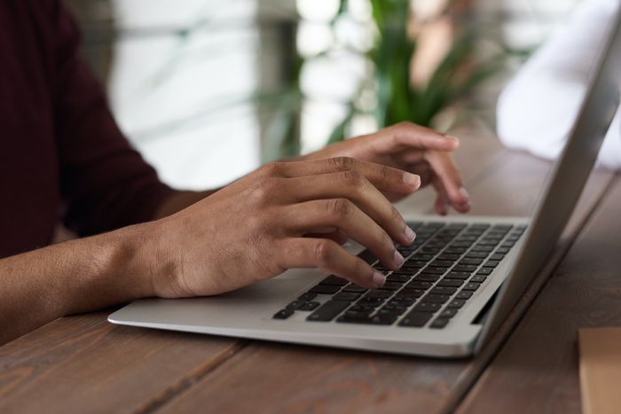 Auf dem Bild zu sehen sind Hände einer Person, die auf einer Laptop-Tastatur liegen