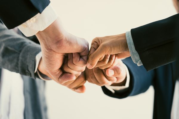 vier Fäuste werden zusammengedrückt als Zeichen der Zusammenarbeit